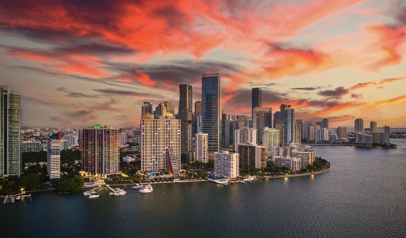 Brickell Key and downtown Miami across Biscayne Bay beneath a sunset sky.