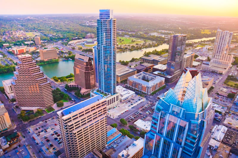 Downtown Austin, Texas, at sunset, with high-rise buildings beside the river.