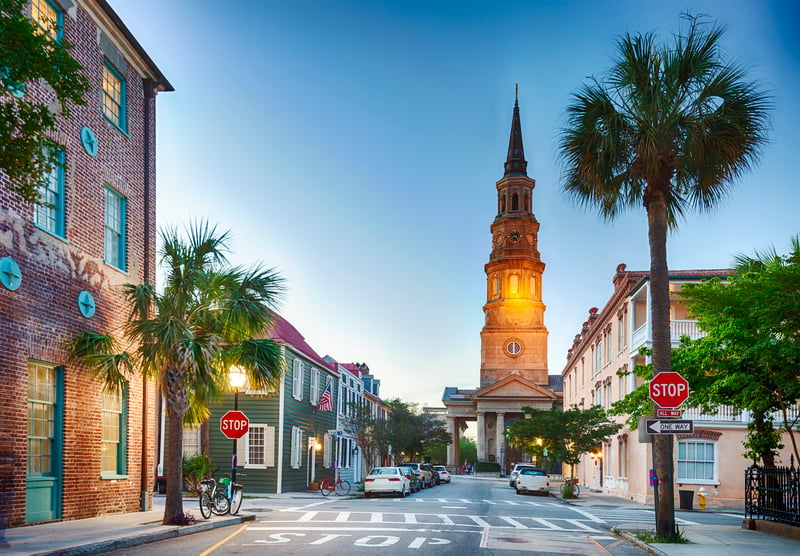 An illuminated church and historic streets in downtown Charleston, South Carolina, at dusk.