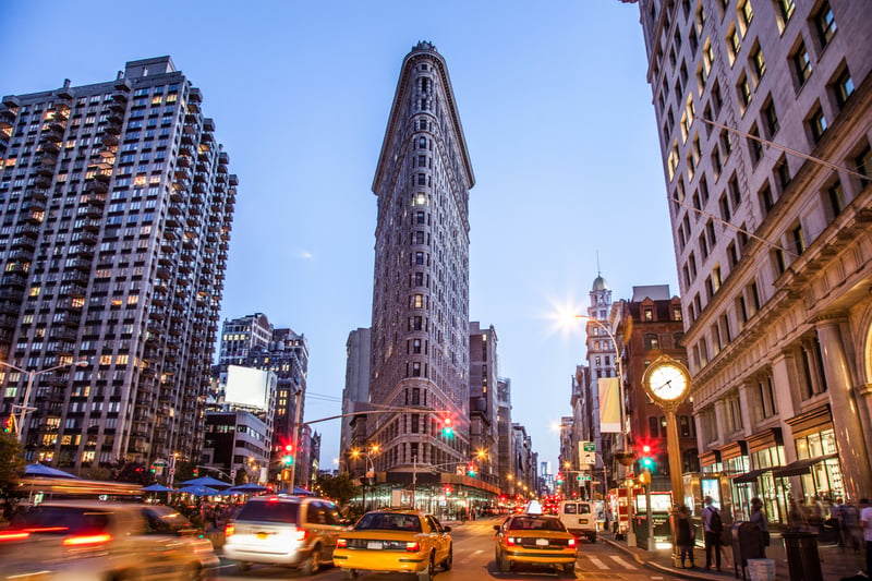 The Flatiron Building at the intersection of Broadway and Fifth Avenue in Manhattan at dusk.