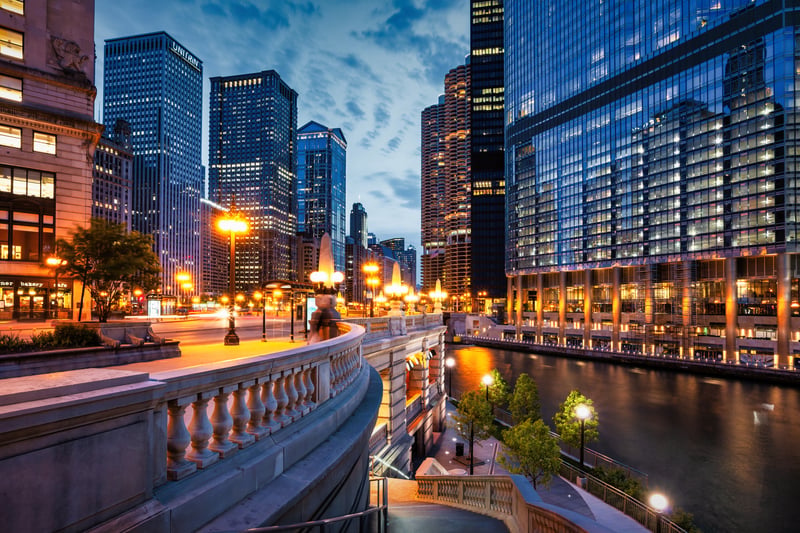 Illuminated skyscrapers and the Riverwalk beside the Chicago River at night.