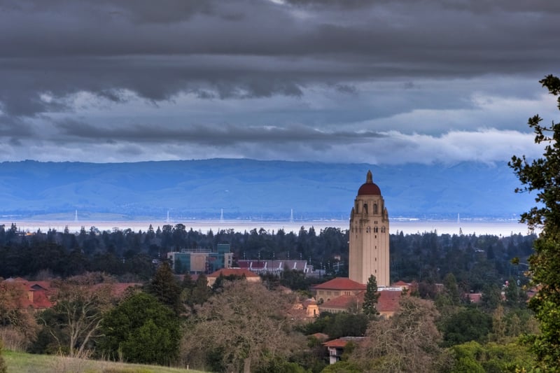 The Palo Alto area of Silicon Valley beneath clouds, with a tower rising above tree-lined grounds.