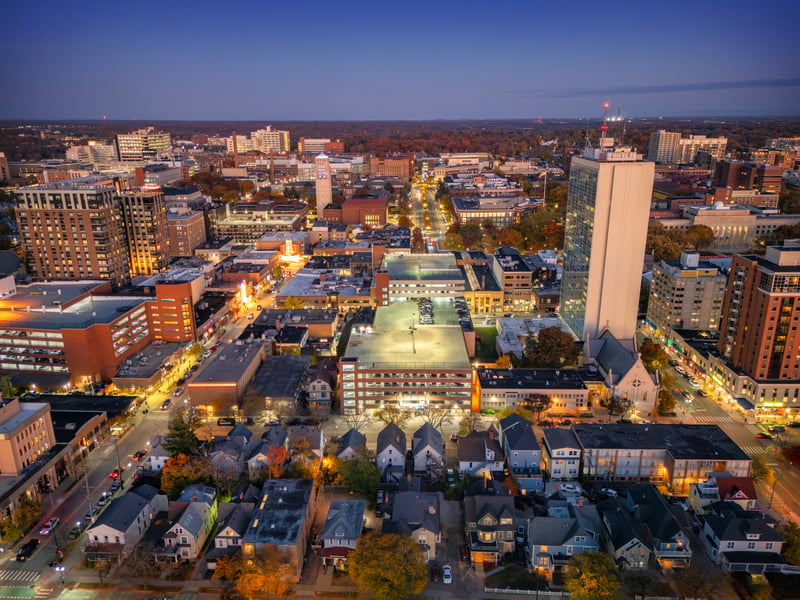 Downtown Ann Arbor, Michigan, at dusk, with homes in the foreground and university buildings beyond.