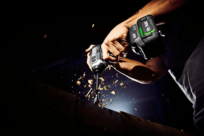 The FLEX 1/4-inch Quick Eject Impact Driver is used to bore a hole in a piece of lumber.