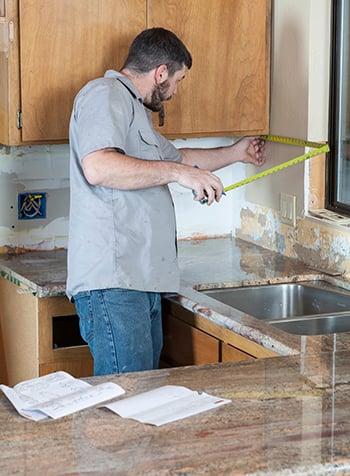 The wall of the backsplash is measured to determine square footage.