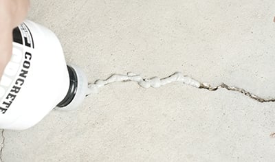 A crack in a concrete floor is filled with concrete filler.