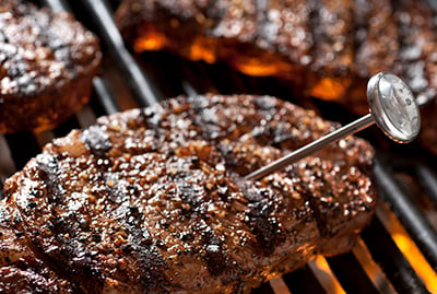 A dial meat thermometer is used to measure the temperature of a steak.