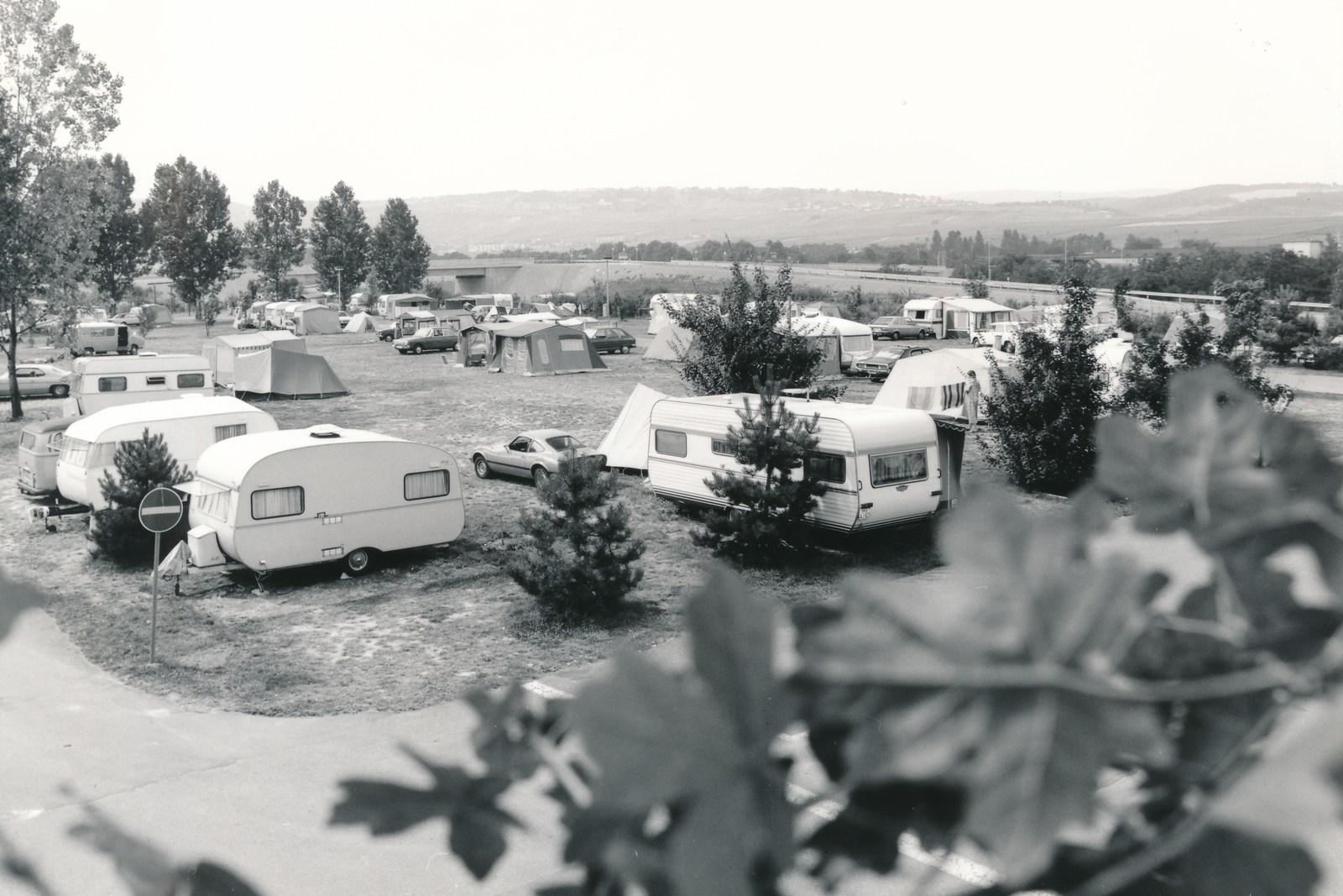 Blik over de vroegere camping met caravans en voortenten, daarachter de heuvels van de Rheingau