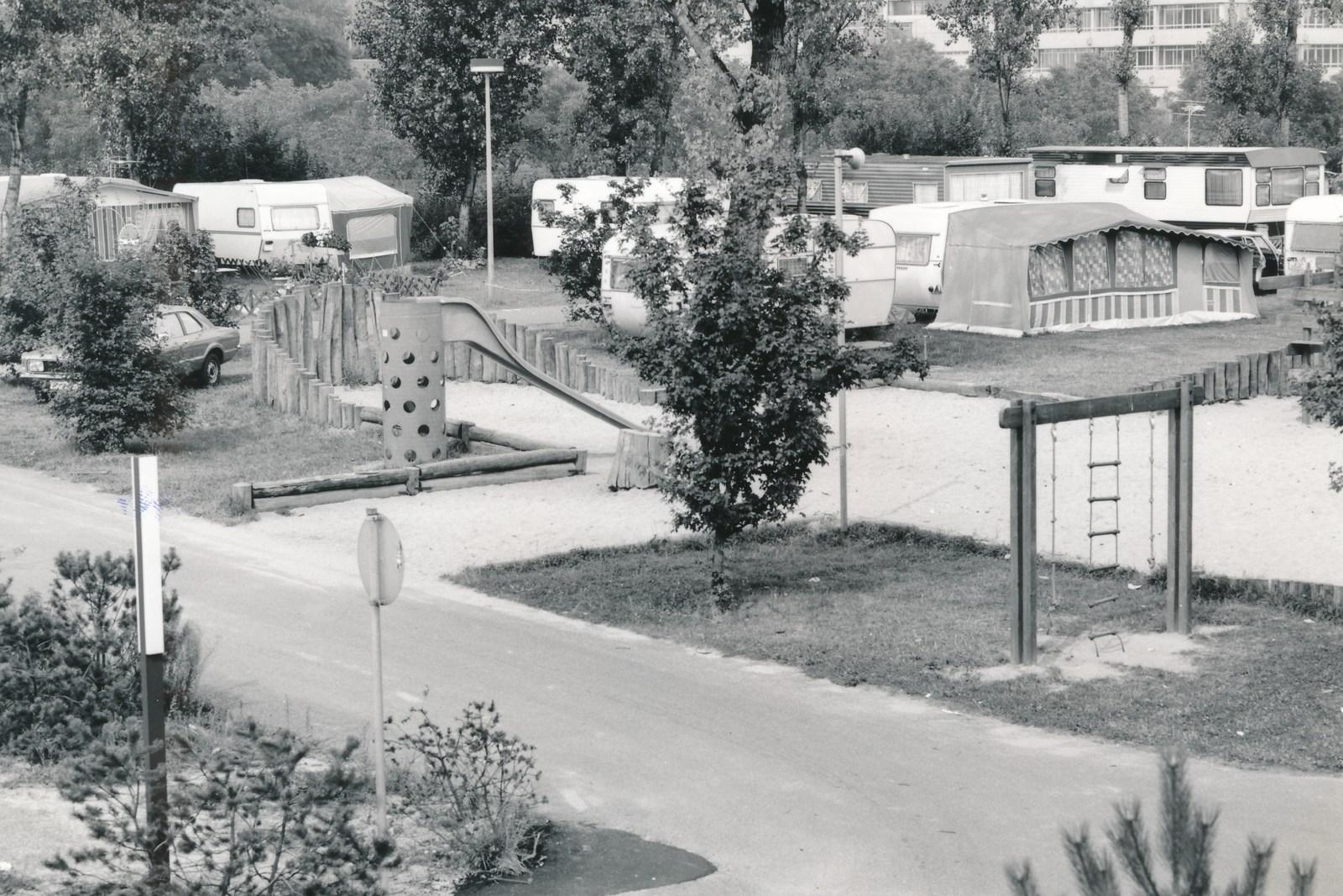De speeltuin van de camping in vroegere jaren – glijbaan, klimrek en schommel, daarachter caravans