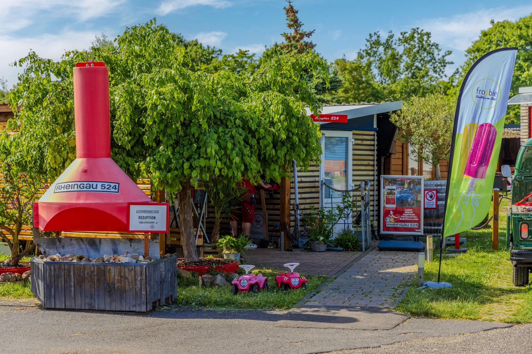 Receptionen hos Rheingau 524 Lodges med en rödmålad vinpress, flaggor och planterade rabatter