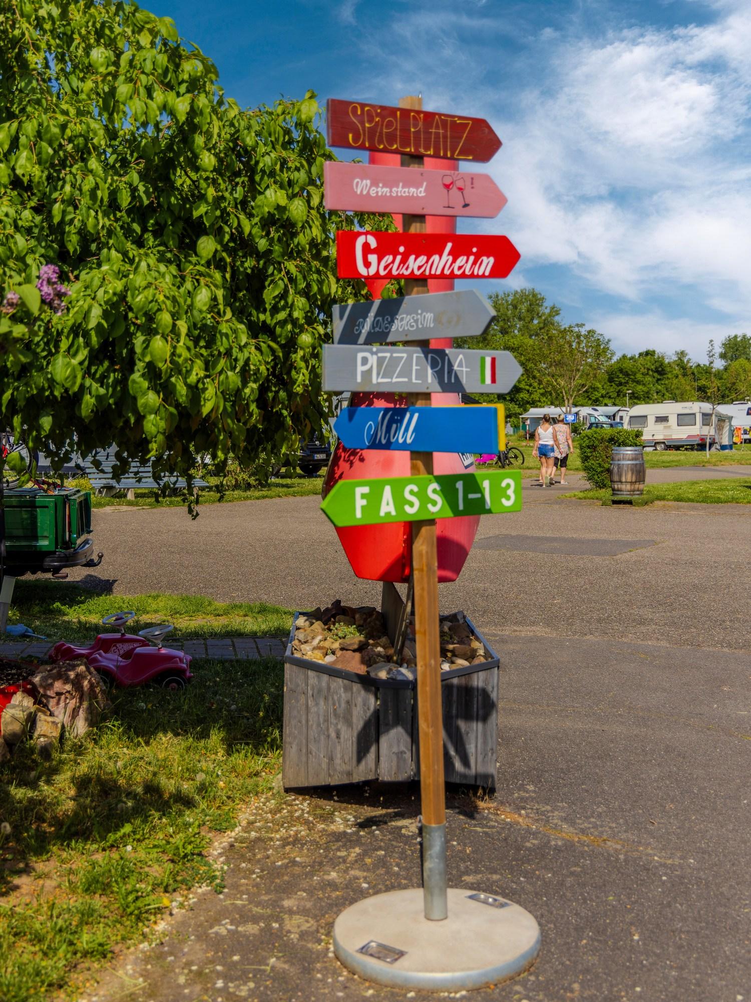 Färgglad vägvisare på Rheingaucamping Geisenheim med skyltar till tunna 1–13, pizzeria, plats och Geisenheim
